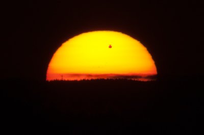 Vychzejc Slunce, zdeformovan atmosfrou, stmavou siluetou Venue. Snmek pozen bnm 400mm teleobjektivem bez filtru.